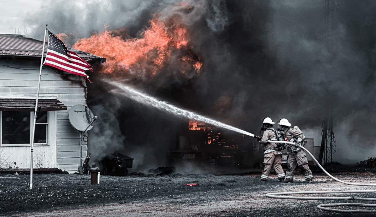 Firefighters fighting house fire in front of american flag